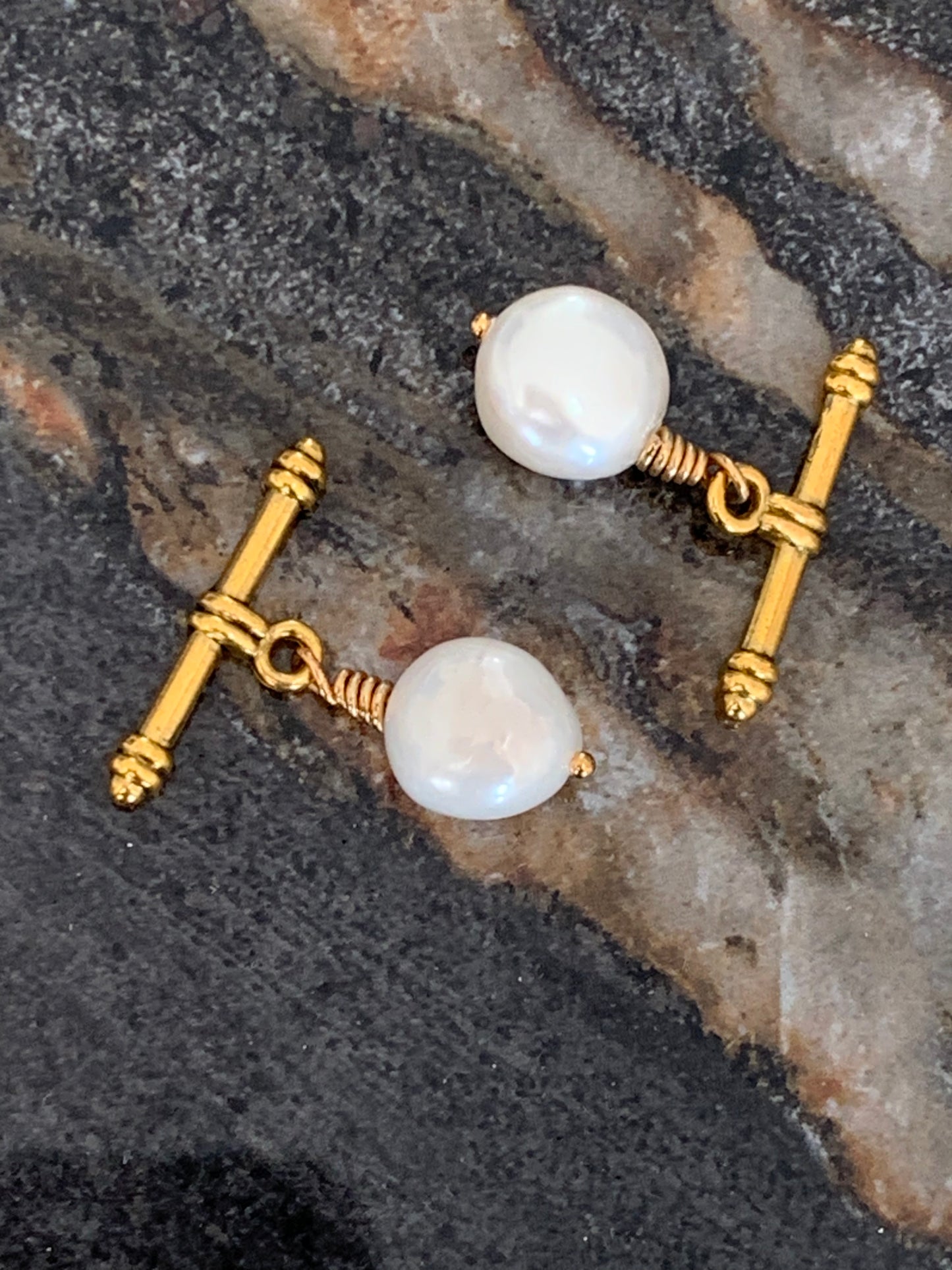 Close up of white baroque pearl cufflinks, cuff links with gold toggles